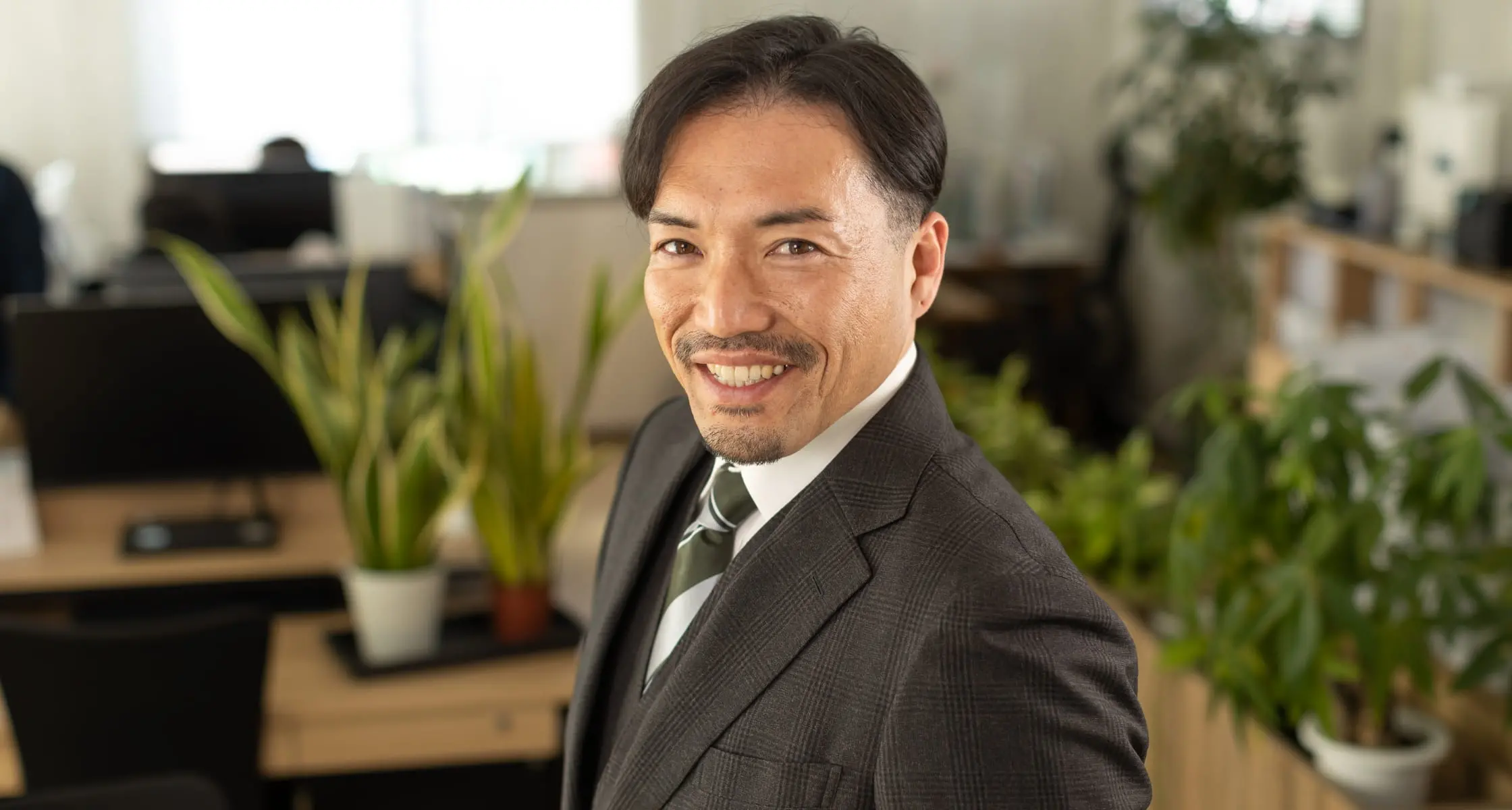 スーツを着た代表取締役がオフィスで微笑む