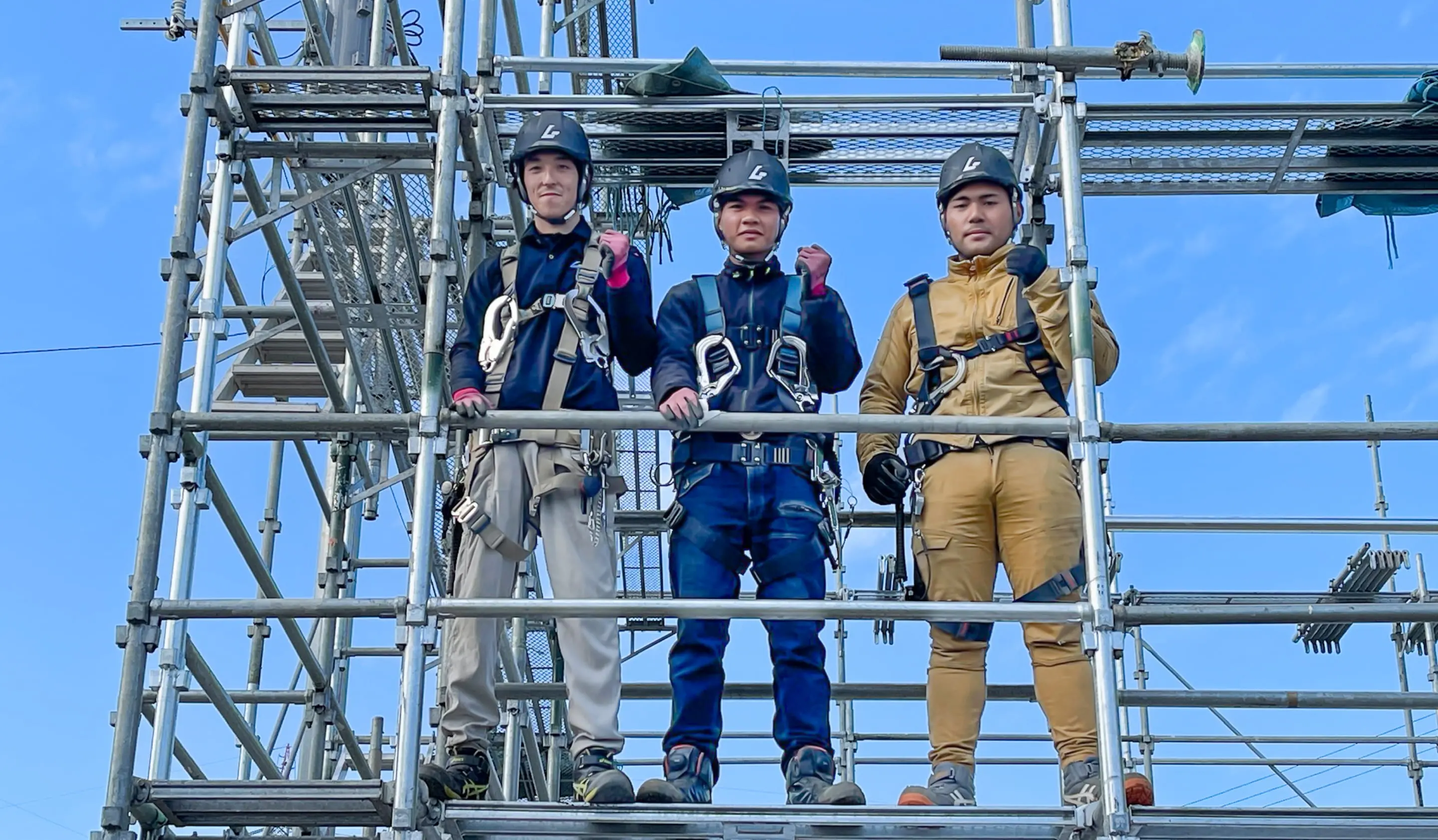 足場でポーズをとる作業員